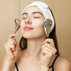 Woman using facial roller devices with a neutral background